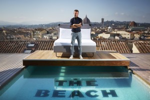 Charlie MacGregor, chief executive officer and founder of The Student Hotel (TSH) at the opening of his first Italian hybrid hotel, TSH Florence Lavagnini.  Charlie is pictured standing in front of a bed on a platform above the rooftop pool in front of the Duomo in the Tuscan capital, Florence.